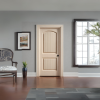 Off-Whiate 2-Panel Grooved Round Top Cheyenne Interior Door in a room with a chair, a vase with green grass, a window looking out at a tree and a picture on the wall.