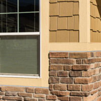 House with window that is part brick and part siding.